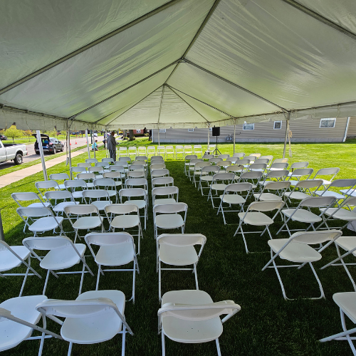 White Chairs Set Up Under A Tent Rental