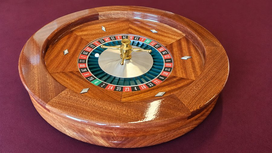 Wooden casino roulette wheel on a burgundy table for a holiday business party, Just In Case Party Rentals